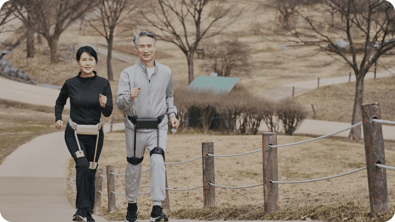 공원 산책로에서 WIM을 착용하고 나란히 걷는 중년 부부
